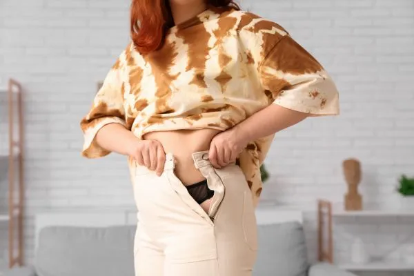Image of woman trying to do her trousers up after pregnancy weight gain Hereford